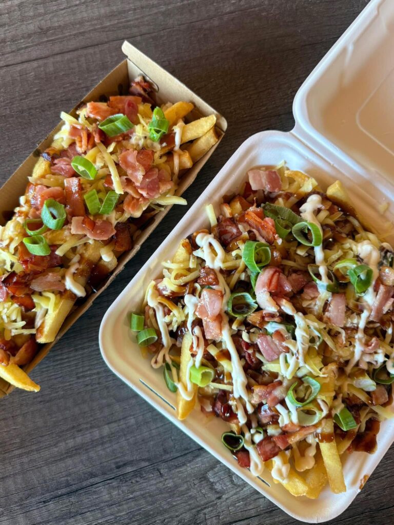 Fully loaded fries topped with melted cheese and crispy bacon bits, served with a side of bbq sauce.