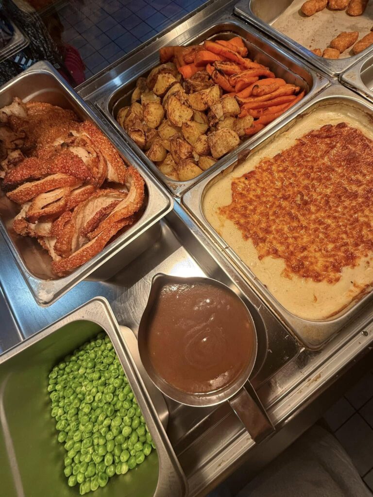 Slow-roasted pork dinner with golden roast potatoes, vegetables, and rich homemade gravy.