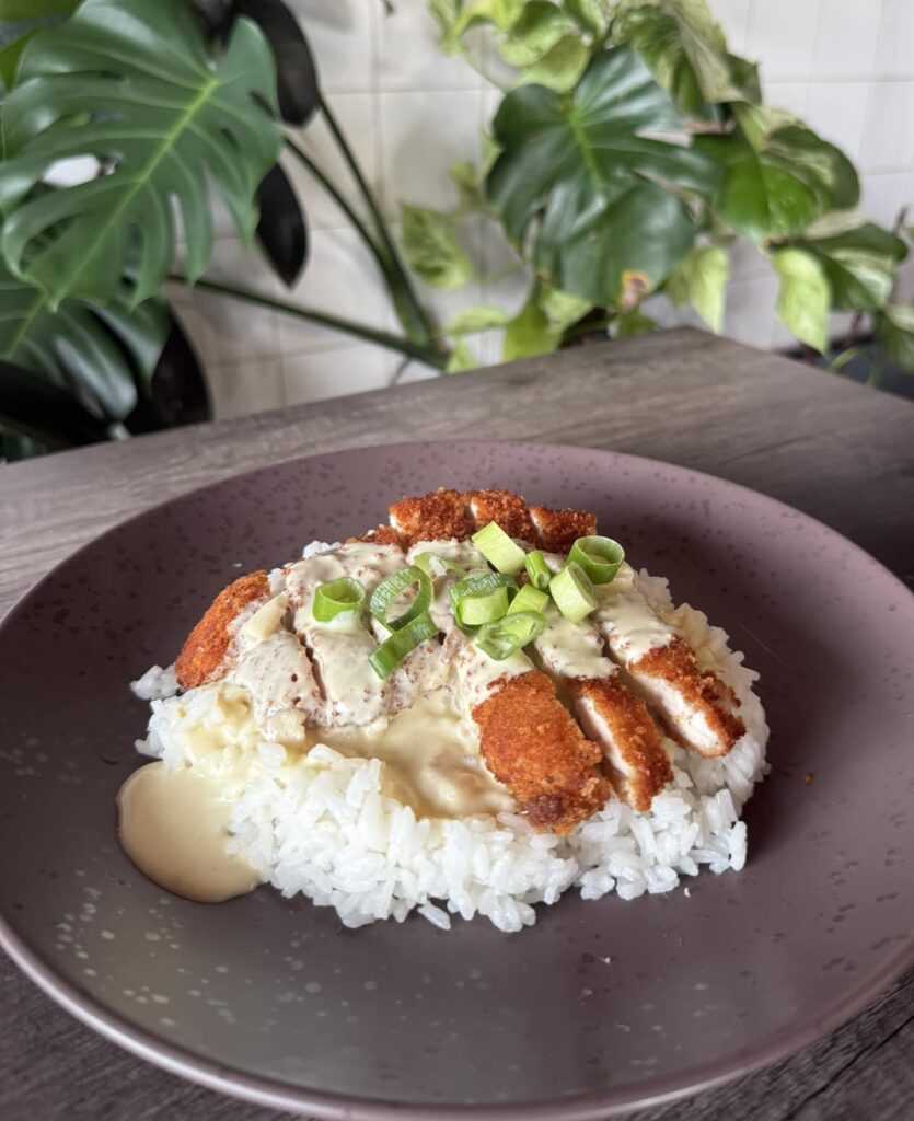 Fried chicken with steamed rice, drizzled with a rich and creamy mushroom sauce, served with fresh herbs.