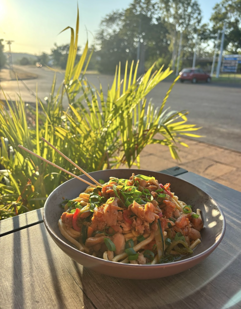 Udon noodle stir fry with vegetables, and a savoury soy-based sauce, garnished with spring onions.